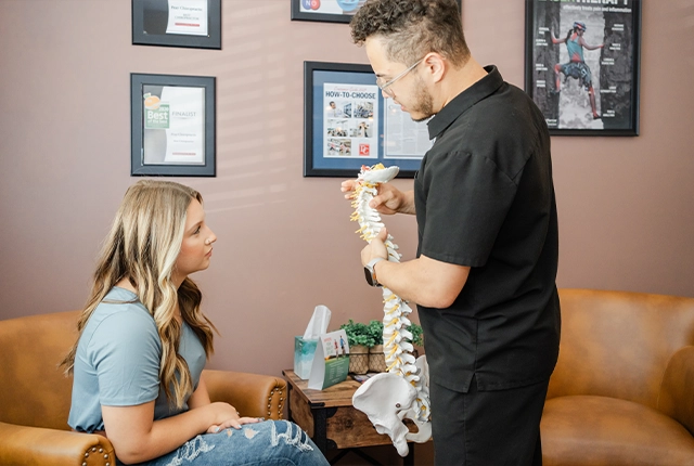 Chiropractor Eric Rivera Gesturing To Spine Model